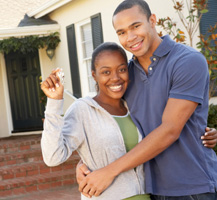 Man and woman holding keys infront of house