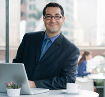 Man dressed in suit sitting at desk working on laptop