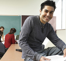 Young man sitting on a desk in a classroom
