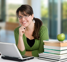 Woman working on laptop and stack of books